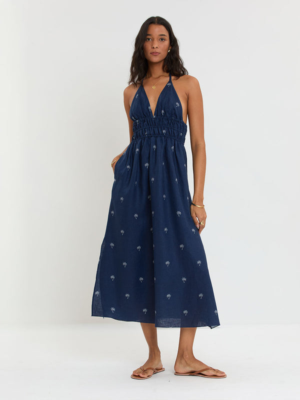 Woman Standing Wearing lemlem GETE Dress featuring ivory palm tree motifs set against a rich navy background.