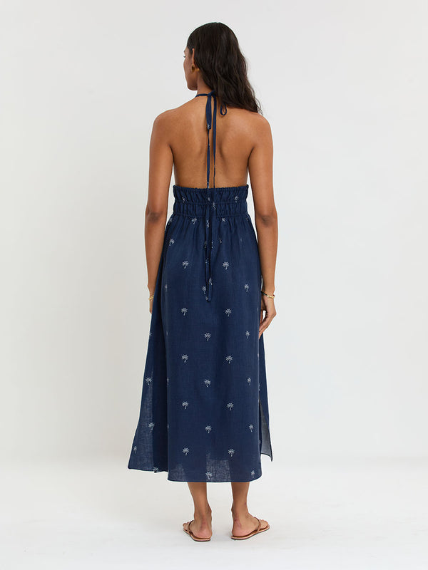 Woman Standing Wearing lemlem GETE Dress featuring ivory palm tree motifs set against a rich navy background.