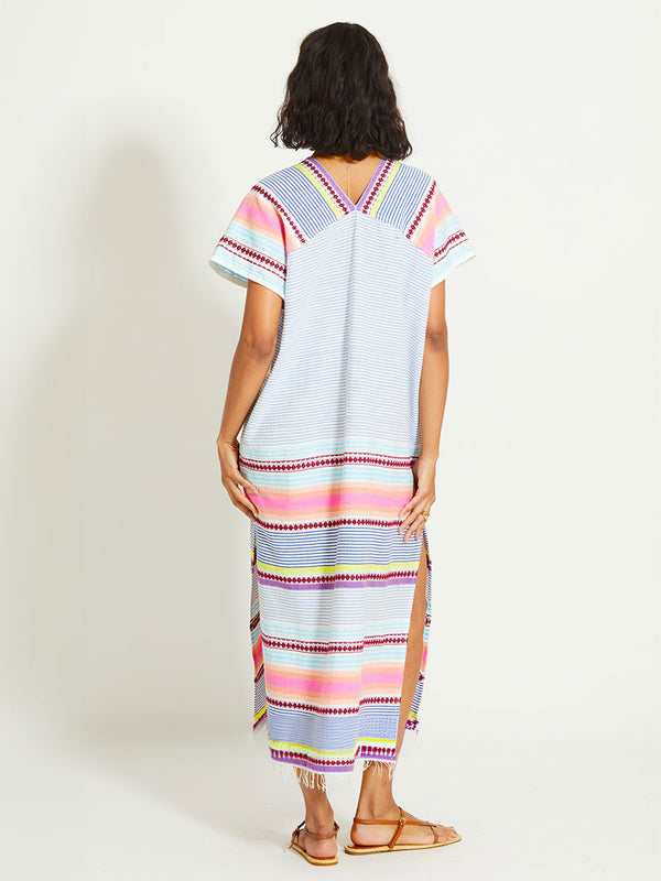 Back of a Woman Standing Wearing lemlem GASIRA | V Neck Caftan featuring  intricate stripes in sun-washed hues and a Tibeb-inspired pattern in rich dark plum
