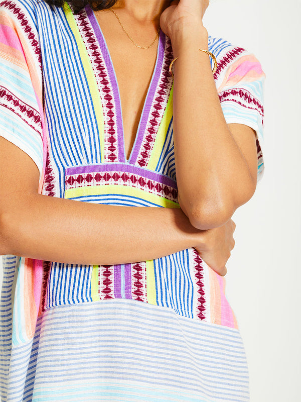 Close up on a Woman Standing Wearing lemlem GASIRA | V Neck Caftan featuring  intricate stripes in sun-washed hues and a Tibeb-inspired pattern in rich dark plum