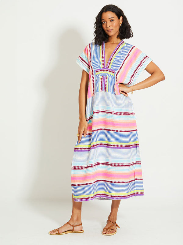 Woman Standing Wearing lemlem GASIRA | V Neck Caftan featuring  intricate stripes in sun-washed hues and a Tibeb-inspired pattern in rich dark plum