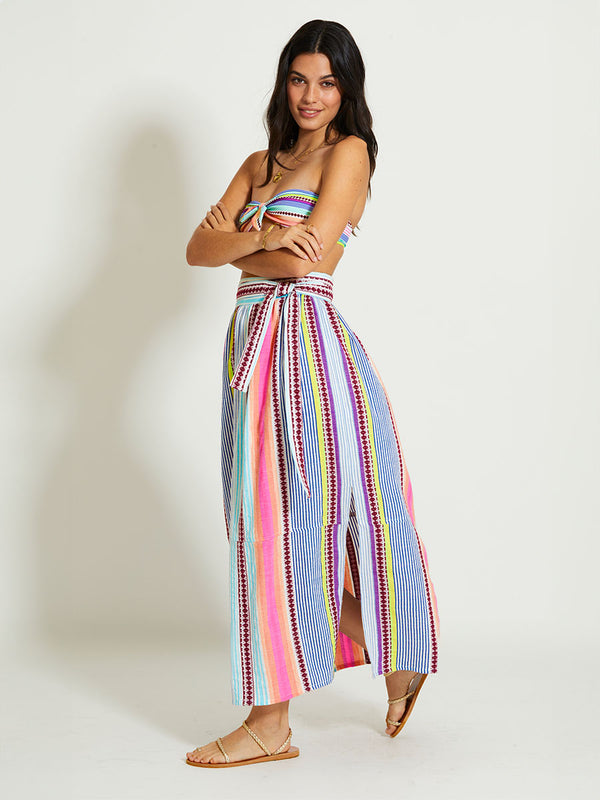 Woman Standing Wearing lemlem TOLA | Skirt featuring  intricate stripes in sun-washed hues and a Tibeb-inspired pattern in rich dark plum