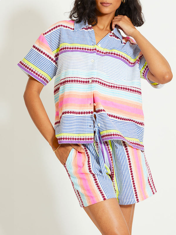 Close up on a Woman Standing Wearing lemlem TUULI | Cabana Shirt featuring  intricate stripes in sun-washed hues and a Tibeb-inspired pattern in rich dark plum