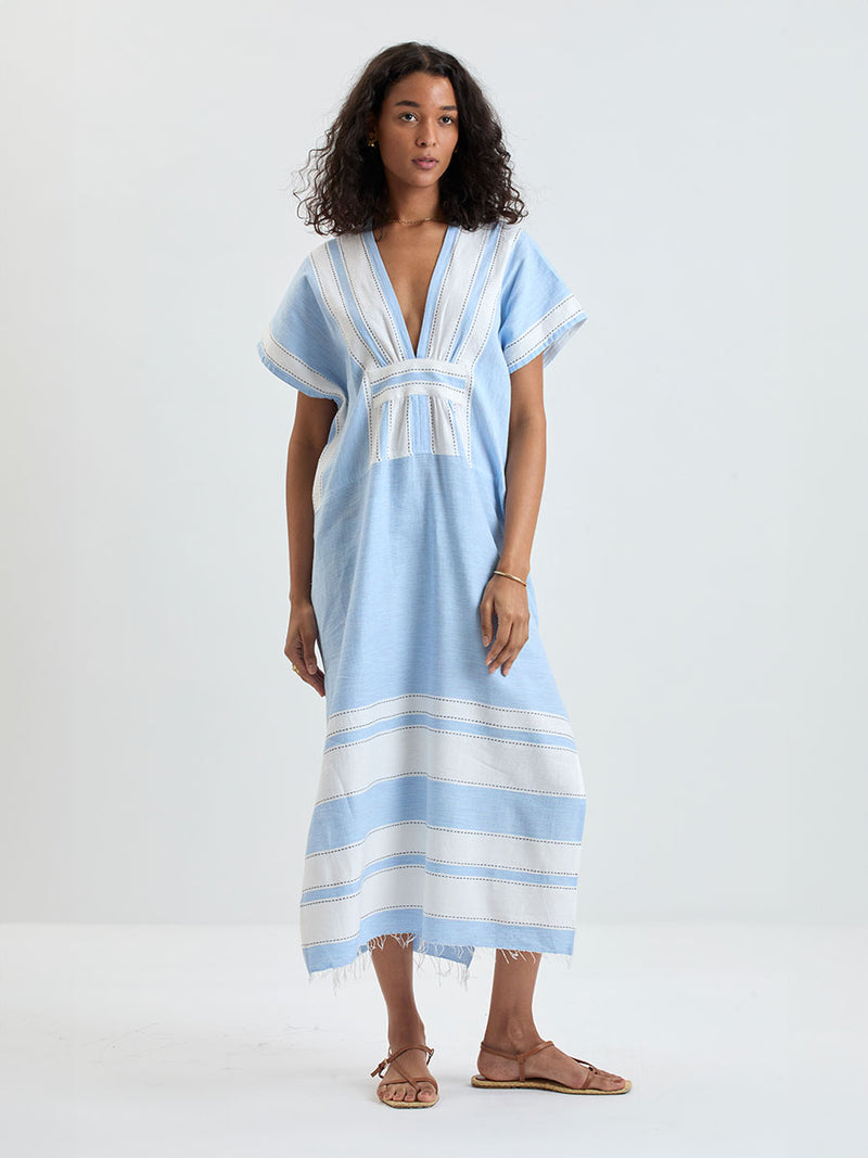 woman wearing lemlem GASIRA Caftan featuring color block stripe pattern in white on sky blue background
