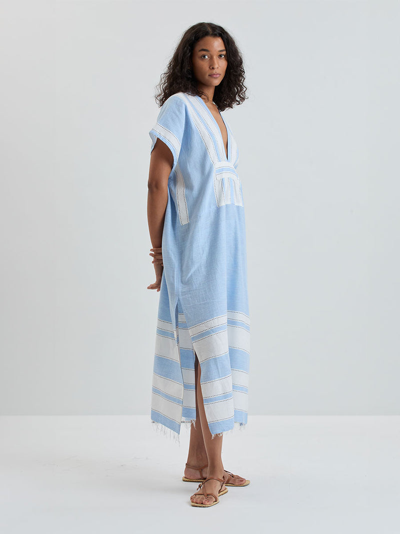 woman wearing lemlem GASIRA Caftan featuring color block stripe pattern in white on sky blue background