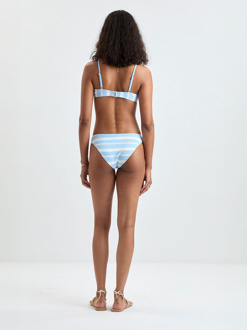 Back of a Woman wearing  lemlem ASHA Scoop Top and MERON Birief Bottom featuring bold, crisp white stripes on a sky-blue background, accented with black detailing.
