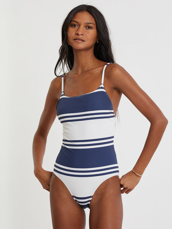 Woman standing wearing lemlem ELENE One Piece featuring bold two-tone stripes in white and classic navy, printed on soft ribbed fabric.