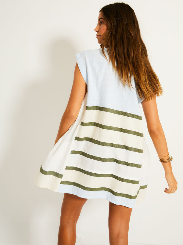 Back of a Woman Standing Wearing lemlem ELINA Caftan featuring a bold asymmetrical color-block pattern, where airy light blue effortlessly blends with soft sage and cream