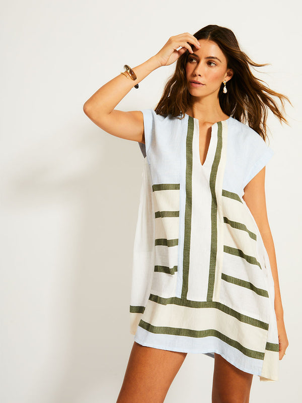 Woman Standing Wearing lemlem ELINA Caftan featuring a bold asymmetrical color-block pattern, where airy light blue effortlessly blends with soft sage and cream