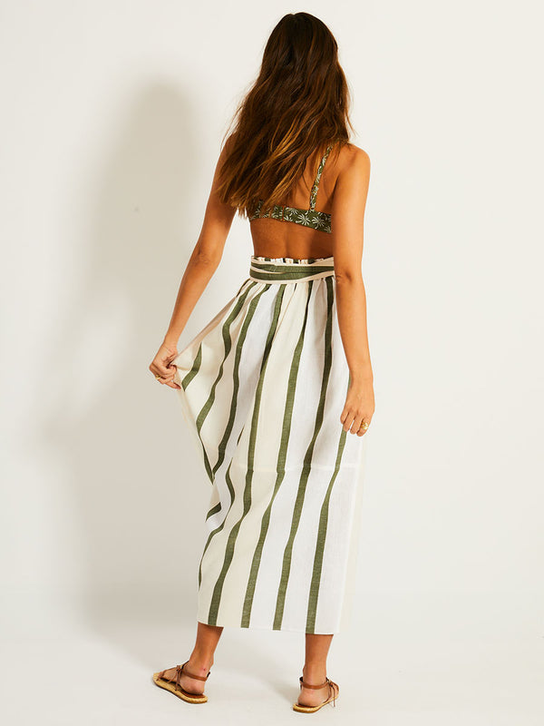 Back of a Woman Standing Wearing lemlem TOLA Skirt featuring a bold asymmetrical color-block pattern, where airy light blue effortlessly blends with soft sage and cream