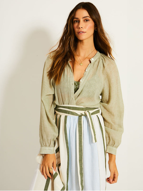 Woman Standing Wearing lemlem TOLA Skirt featuring a bold asymmetrical color-block pattern, where airy light blue effortlessly blends with soft sage and cream