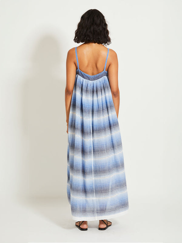 Back of a woman standing wearing lemlem EDA Slip dress featuring ombre pattern in navy, blue, pale blue and white colors