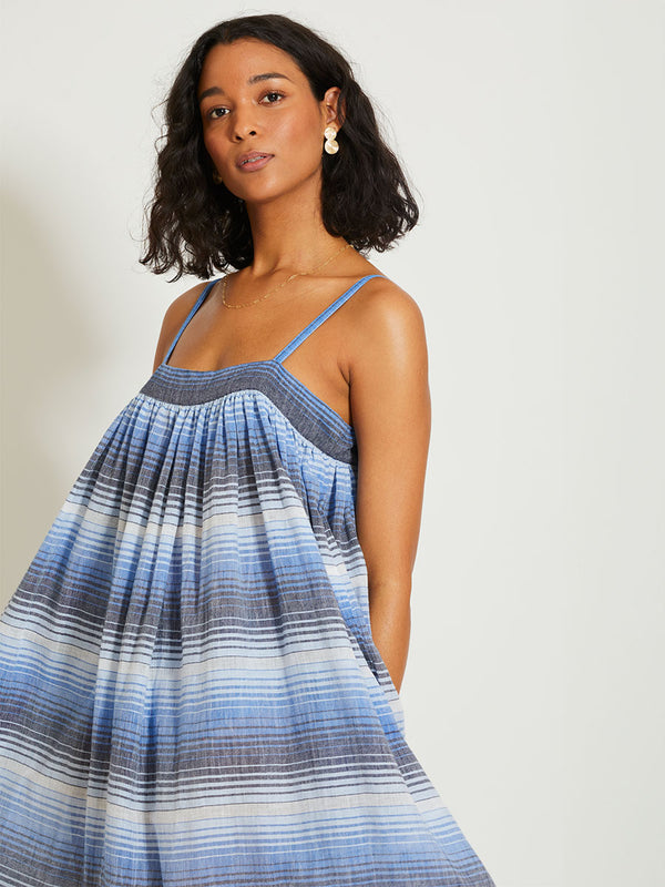 Woman Standing wearing lemlem EDA Slip dress featuring ombre pattern in navy, blue, pale blue and white colors