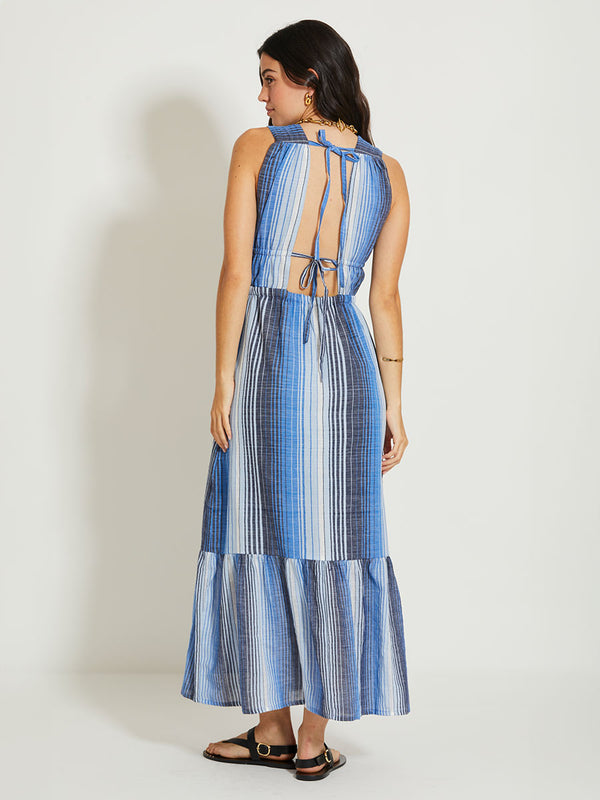 Woman Standing Wearing lemlem LELISA | V Neck Dress featuring  stripe pattern that blends into a stunning ombré effect, with soft transitions between white, sky blue, mid blue, and deep navy.
