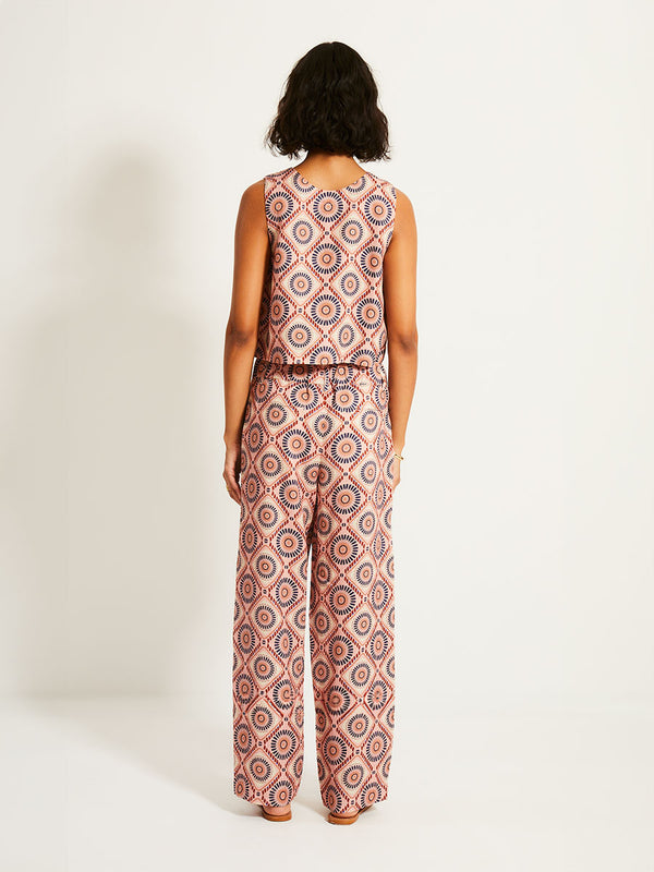 Back of a Woman Standing Wearing lemlem DIARRA | Pants  featuring a Yani Tibeb-inspired pattern in peach, rust, and orchid hues, accented with a bold citrus yellow pop and matching vest
