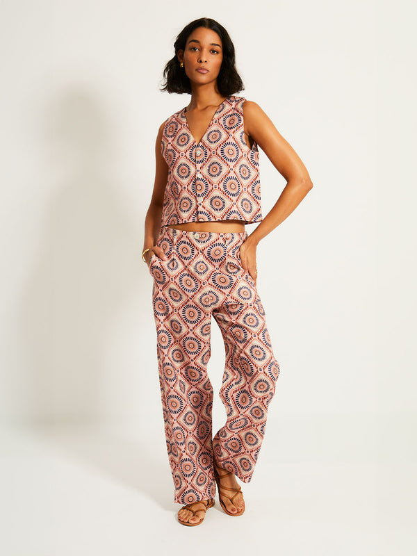 Woman Standing Wearing lemlem DIARRA | Pants  featuring a Yani Tibeb-inspired pattern in peach, rust, and orchid hues, accented with a bold citrus yellow pop.
