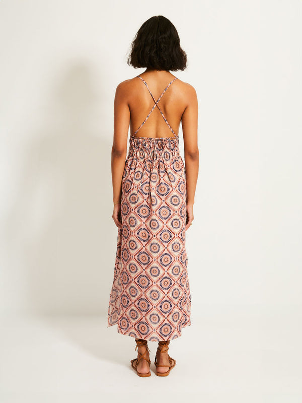 Back of a Woman Standing Wearing lemlem GETE | Triangle Dress featuring a Yani Tibeb-inspired pattern in peach, rust, and orchid hues, accented with a bold citrus yellow pop.

