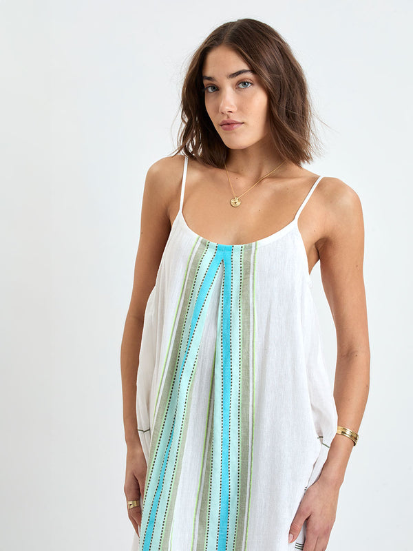 Close up on a Woman wearing lemlem NIA Slip Dress featuring a chic stripe pattern in aqua blue and sage tones, delineated by dark olive dots and accented with a splash of neon yellow on a cream background 