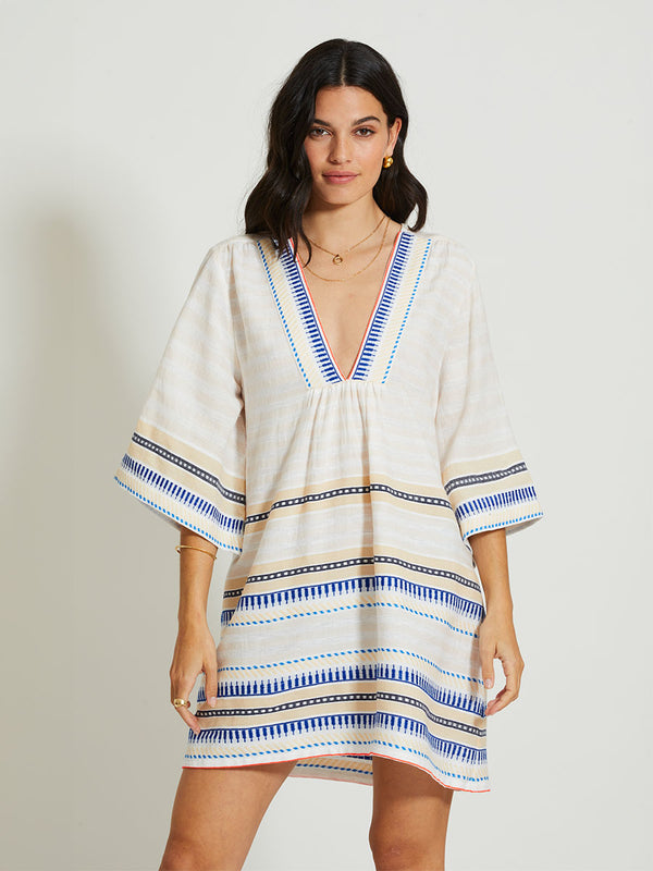 Woman Standing Wearing lemlem BELKIS | V Neck Caftan featuring a soft shadow stripe base with graphic Tibeb-inspired bands in rich blues, black, and vanilla on a creamy white ground
