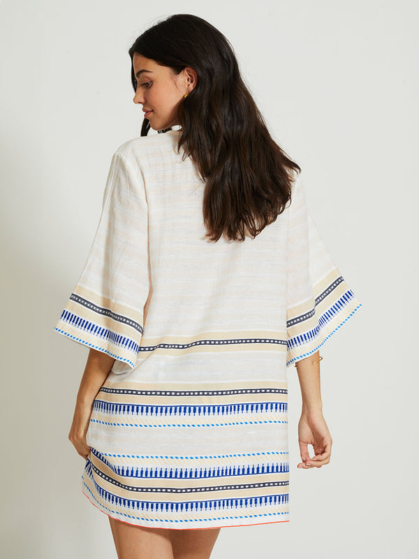 Back of a Woman Standing Wearing lemlem BELKIS | V Neck Caftan featuring a soft shadow stripe base with graphic Tibeb-inspired bands in rich blues, black, and vanilla on a creamy white ground