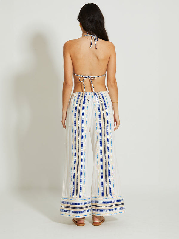 Back of a Woman Standing Wearing lemlem DESTA | Pants featuring a soft shadow stripe base with graphic Tibeb-inspired bands in rich blues, black, and vanilla on a creamy white ground