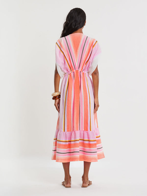 Woman standing wearing lemlem handwoven  LEILA Dress featuring intricate stripe pattern interlaced with delicate mini Tibeb detailing, expressed in a soft yet vivid palette of cool pink, warm tangerine, rose, orchid, and accents of peach and deep burgundy.