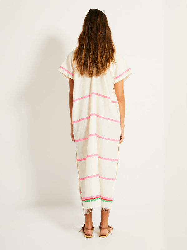 Back of a Woman Standing Wearing lemlem GASIRA Caftan featuring a playful, preppy scalloped Tibeb weave with vibrant green, soft pink, and fiery red accents
