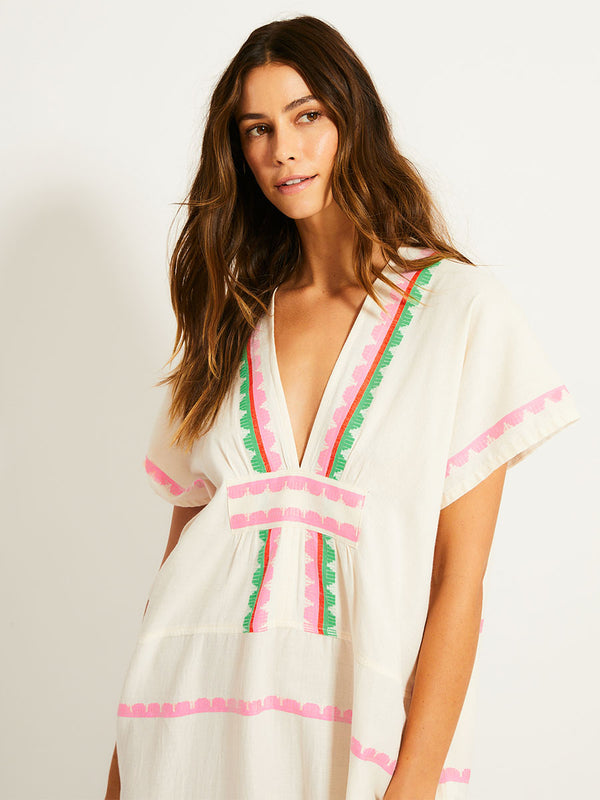 Close up on a Woman Standing Wearing lemlem GASIRA Caftan featuring a playful, preppy scalloped Tibeb weave with vibrant green, soft pink, and fiery red accents
