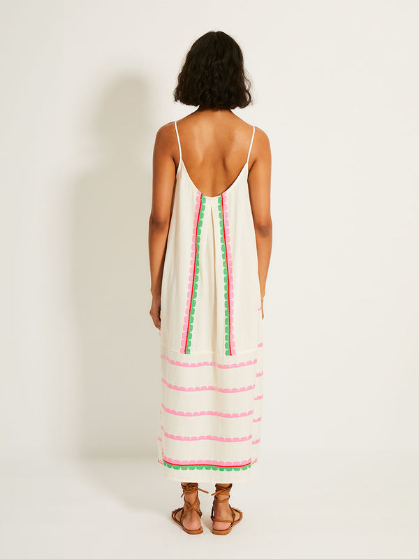 Back of a Woman Standing Wearing lemlem NIA Slip Dress featuring a playful, preppy scalloped Tibeb weave with vibrant green, soft pink, and fiery red accents

