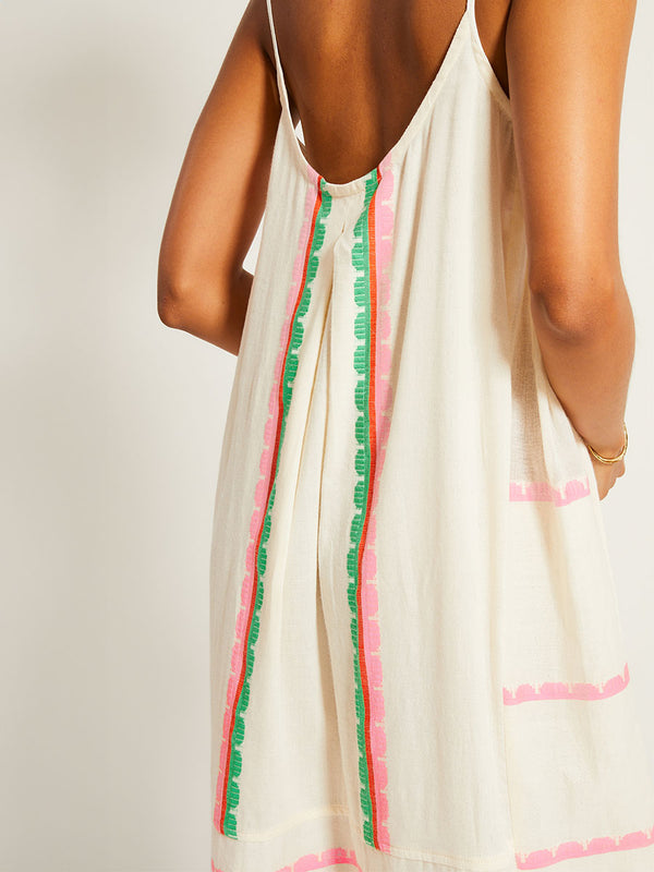 Close up on a Woman's back Standing Wearing lemlem NIA Slip Dress featuring a playful, preppy scalloped Tibeb weave with vibrant green, soft pink, and fiery red accents
