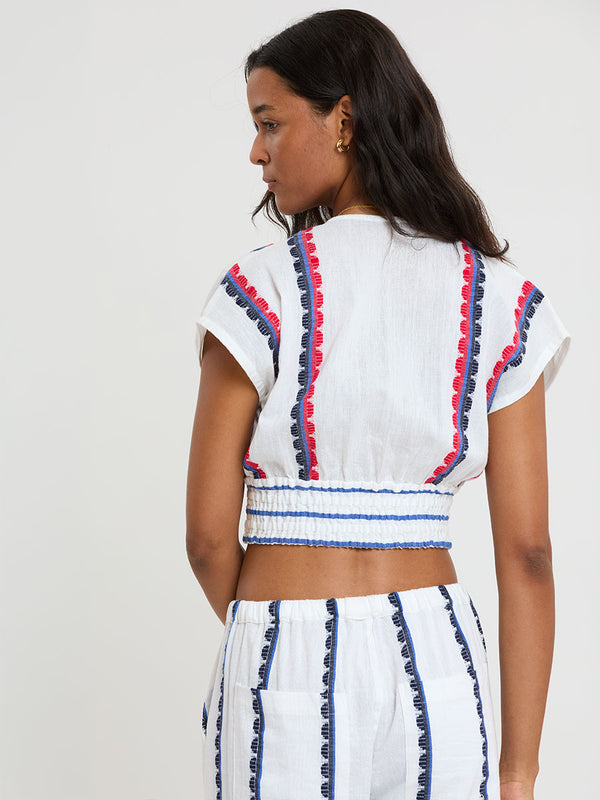 Back of a Woman Standing wearing lemlem handwoven ALIA Plunge Top and DESTA Pants featuring a playful, preppy scalloped Tibeb weave with classic navy, red, and vibrant blue accents.