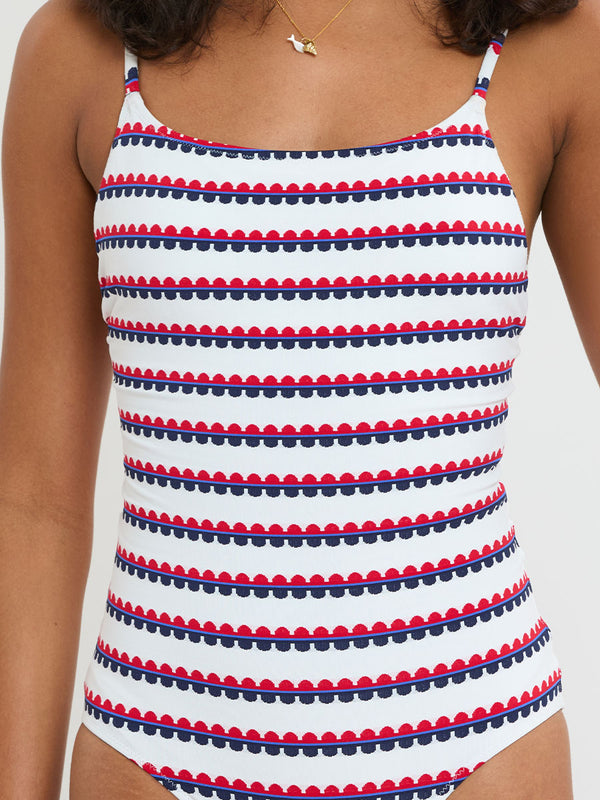Woman Standing wearing lemlem ELENE One Piece featuring a playful, preppy scalloped Tibeb weave with classic navy, red, and vibrant blue accents.