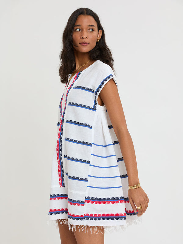 Woman Standing wearing lemlem handwoven ELINA Caftan featuring a playful, preppy scalloped Tibeb weave with classic navy, red, and vibrant blue accents.