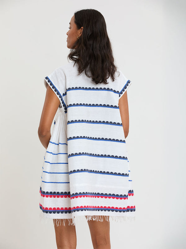 Woman Standing wearing lemlem handwoven ELINA Caftan featuring a playful, preppy scalloped Tibeb weave with classic navy, red, and vibrant blue accents.