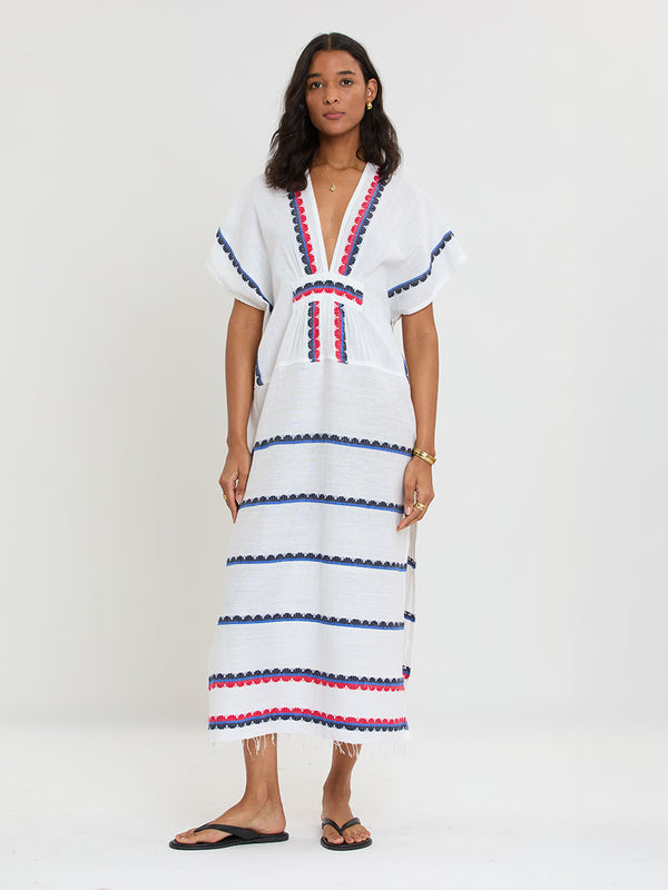 Woman Standing wearing lemlem handwoven GASIRA Caftan featuring a playful, preppy scalloped Tibeb weave with classic navy, red, and vibrant blue accents.