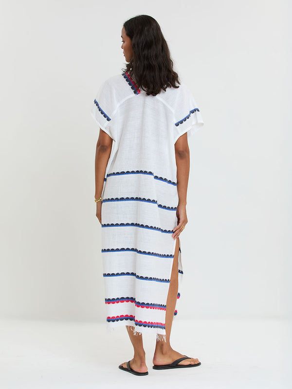 Woman Standing wearing lemlem handwoven GASIRA Caftan featuring a playful, preppy scalloped Tibeb weave with classic navy, red, and vibrant blue accents.