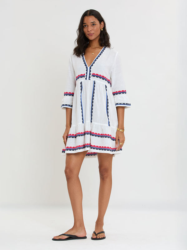 Woman Standing wearing lemlem handwoven HANNA Dress featuring a playful, preppy scalloped Tibeb weave with classic navy, red, and vibrant blue accents.