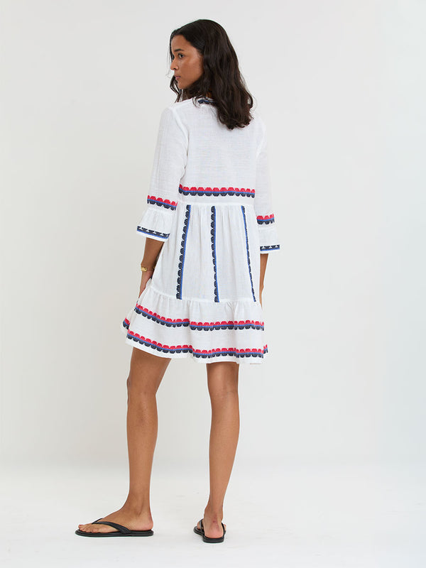 Woman Standing wearing lemlem handwoven HANNA Dress featuring a playful, preppy scalloped Tibeb weave with classic navy, red, and vibrant blue accents.