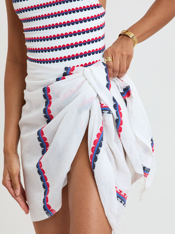 Woman Standing wearing lemlem ELENE One Piece and LEMA Sarong featuring a playful, preppy scalloped Tibeb weave with classic navy, red, and vibrant blue accents.