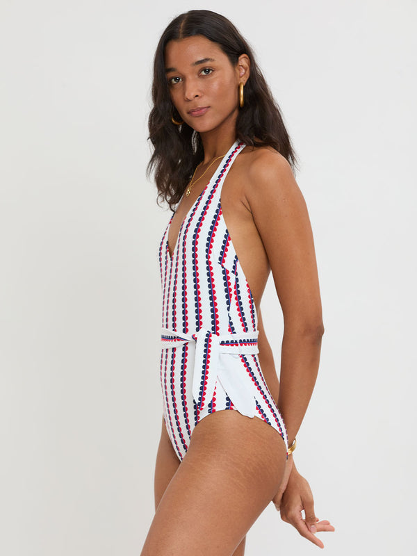 Woman Standing wearing lemlem LIDYA One Piece featuring a playful, preppy scalloped Tibeb weave with classic navy, red, and vibrant blue accents.