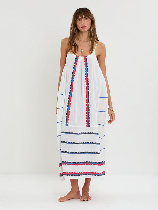 Woman Standing wearing lemlem handwoven NIA Dress featuring a playful, preppy scalloped Tibeb weave with classic navy, red, and vibrant blue accents.