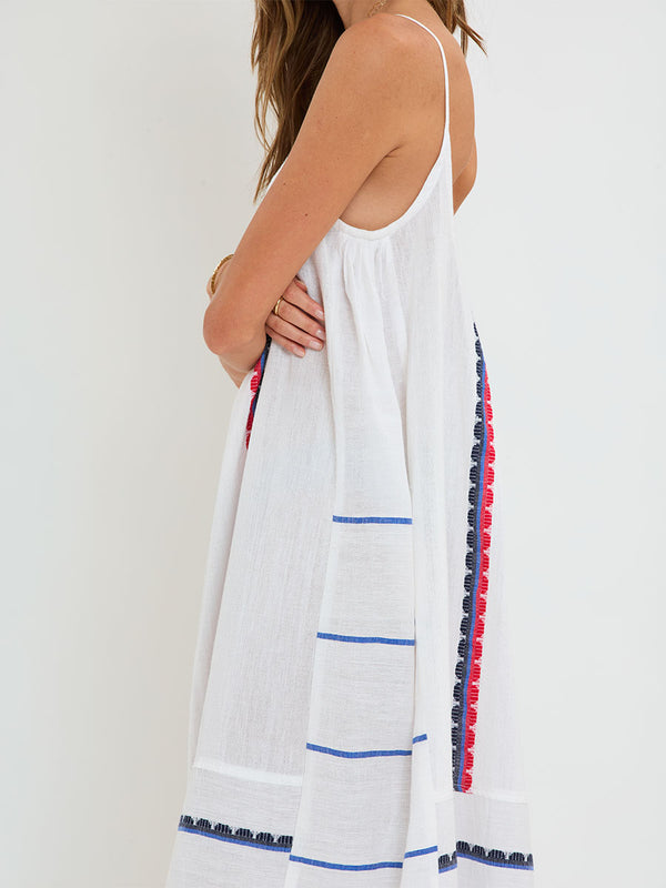 Woman Standing wearing lemlem handwoven NIA Dress featuring a playful, preppy scalloped Tibeb weave with classic navy, red, and vibrant blue accents.