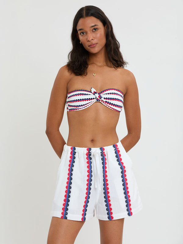 Woman Standing wearing lemlem handwoven SAFIA Shorts featuring a playful, preppy scalloped Tibeb weave with classic navy, red, and vibrant blue accents.