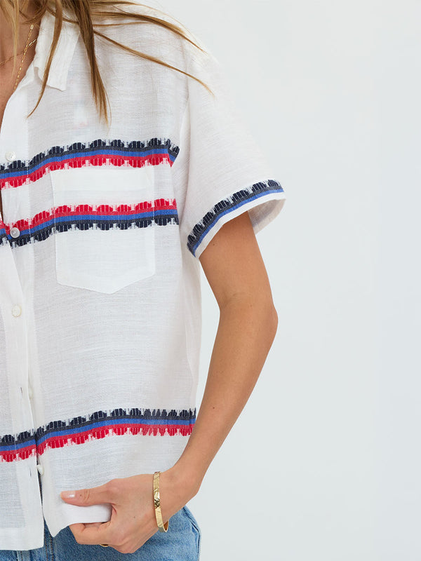 Woman Standing wearing lemlem handwoven TUULI Cabana Shirt featuring a playful, preppy scalloped Tibeb weave with classic navy, red, and vibrant blue accents.
