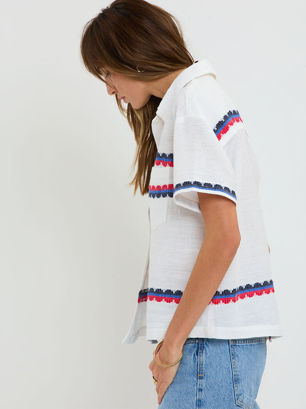 Woman Standing wearing lemlem handwoven TUULI Cabana Shirt featuring a playful, preppy scalloped Tibeb weave with classic navy, red, and vibrant blue accents.