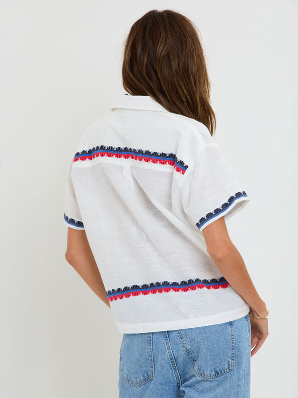 Woman Standing wearing lemlem handwoven TUULI Cabana Shirt featuring a playful, preppy scalloped Tibeb weave with classic navy, red, and vibrant blue accents.