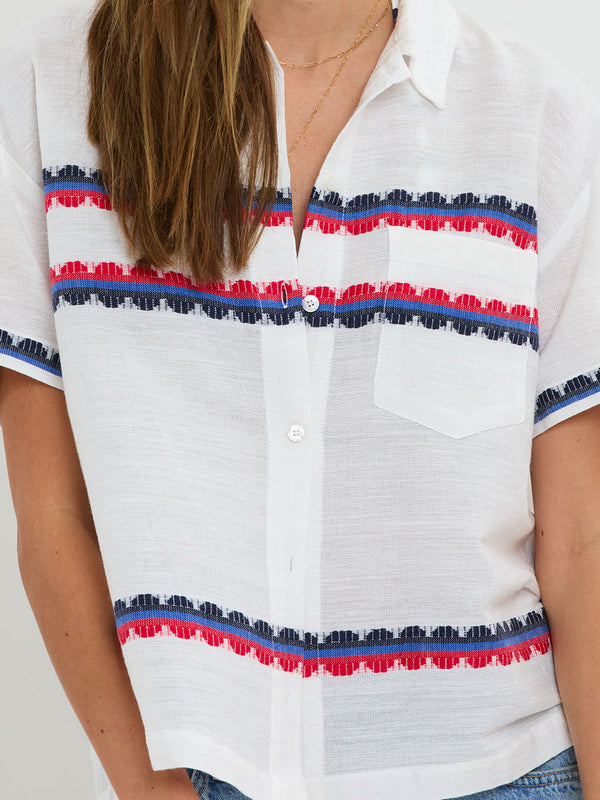 Woman Standing wearing lemlem handwoven TUULI Cabana Shirt featuring a playful, preppy scalloped Tibeb weave with classic navy, red, and vibrant blue accents.