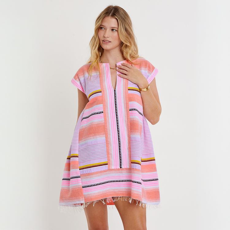 Woman wearing a colorful striped lemlem ELINA Caftan on a plain background