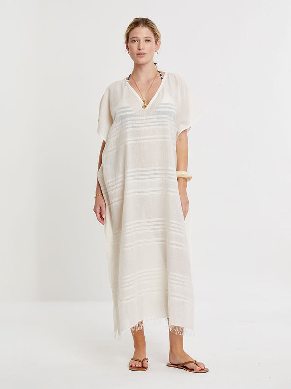 Woman standing wearing lemlem handwoven DALILA Caftan featuring extra light gauzy cotton in a delicate cream color.