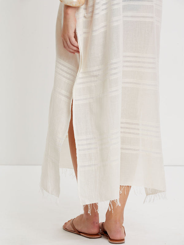 Close up on a Woman standing wearing lemlem handwoven DALILA Caftan featuring extra light gauzy cotton in a delicate cream color.